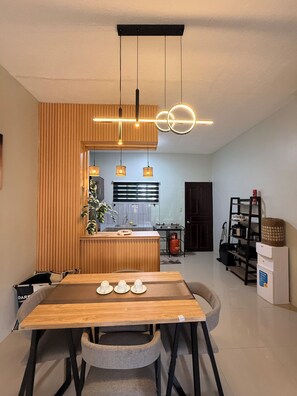 Una cocina moderna con un muro decorativo de madera, iluminación colgante y un comedor con mesa y sillas.