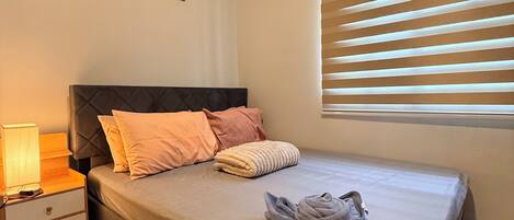 A bedroom with a bed, nightstand, lamp, and an air conditioning unit.