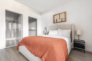 Ein modernes Schlafzimmer mit einem Bett, einem Nachttisch, einer Lampe, einem Kleiderschrank und einer Dusche.