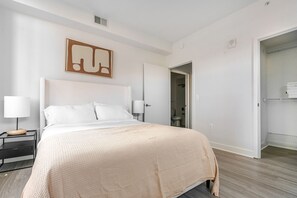 Ein Schlafzimmer mit einem Bett, Nachttischen, einem Kleiderschrank und einem durchgegangenen Tür ersichtlichen Badezimmer.