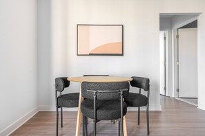 Ein Zimmer mit einem runden Tisch, vier Stühlen, einem gerahmten Bild an der Wand und einer Tür im Hintergrund.