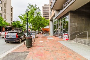 A street view with a brick sidewalk, parked cars, and a building with a sign reading "Bainbridge". - Blueground | Woodmont Triangle, rooftop pool, nr Cabin John Regional Park (Bethesda)