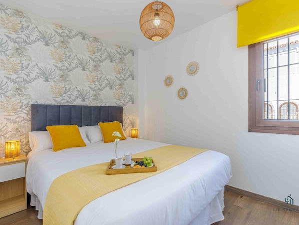 Ein Schlafzimmer mit Bett, Nachttischen, Fenster und Wand mit Dekoration.