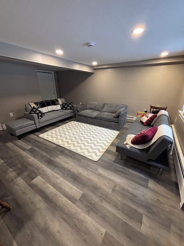 A living room with a gray sectional sofa, a gray loveseat, and a patterned rug.
