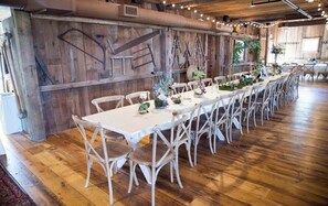 Una larga mesa de comedor con sillas, paredes de madera y un interior rústico.