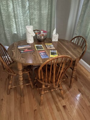 A dining table with a bowl, tissue box, and magazines.