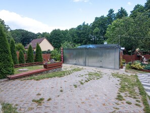 Ein gepflasterter Patio-Bereich mit einem Metallschuppen, Holzzaun und einem Haus im Hintergrund.