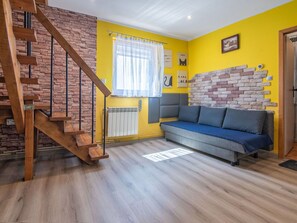 Ein Wohnzimmer mit einer Holztreppe, einer Couch, einer Heizung und einer Ziegelwand.