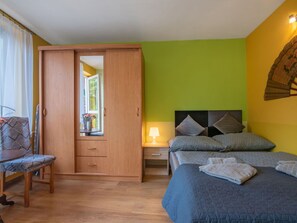 Um quarto com uma cama, mesa de cabeceira, cadeira e armário.