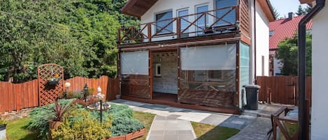 A two-story house with a balcony, a fenced garden, and a paved walkway.
