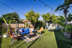 Ein Garten mit einer Terrassenfläche, Gartenmöbeln und verschiedenen Pflanzen.