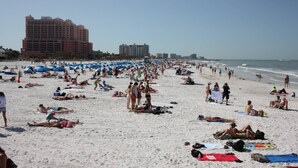 En fullsatt strand med många parasoller och folk som solar.