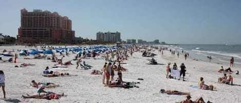 En fullsatt strand med många parasoller och folk som solar.