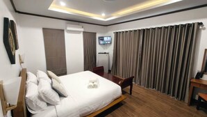 A hotel room with a bed, a desk, a television, and curtains. - Ladda Garden Home  (Muang)