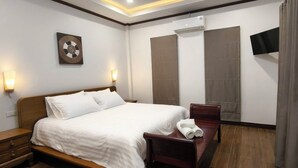 A hotel room with a bed, bedside table, wall-mounted TV, and a large window with curtains. - Ladda Garden Home  (Muang)