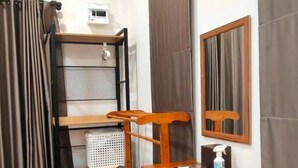 Una habitación con un escritorio de madera, una silla, una cama con cabecera, una ventana con cortinas y una lámpara en el techo.
