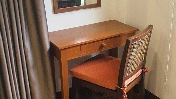 Un escritorio de madera con una silla, un espejo y una cortina.