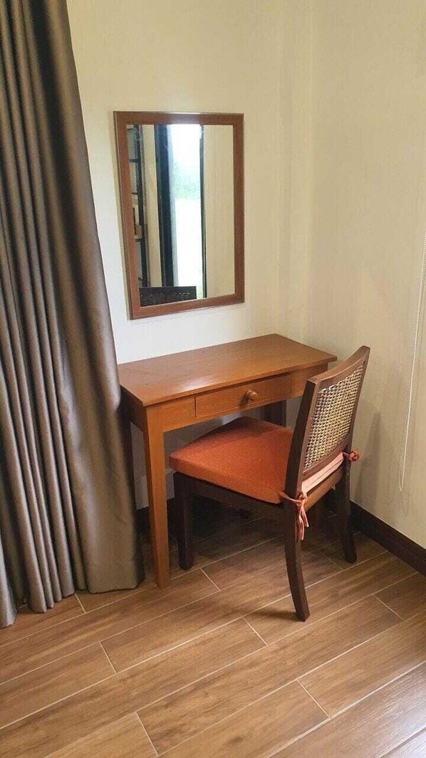 Un escritorio de madera con una silla, un espejo y una cortina.