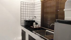 Una cocina compacta con microondas integrado, un lavamanos y un refrigerador.
