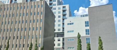 Un edificio moderno con una fachada singular, rodeado de vegetación y un cielo despejado.