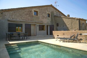 A building with a pool, outdoor seating, and a brick wall.
