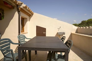 Un patio exterior con una mesa, sillas, una puerta y un ventanal pequeño.