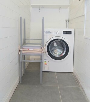 Ein kleiner Waschraum mit einer Bosch Waschmaschine und einem Wäscheständer aus Metall.