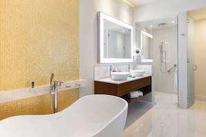 Un baño moderno con una bañera independiente, dos lavamanos, un espejo grande y una cabina de ducha de vidrio.