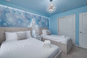 Une chambre d’hôtel avec deux lits, un lustre et une porte.