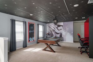 Une pièce dotée d’une table de billard, d’une grande fresque murale et d’un plafond décoré de motifs étoilés.