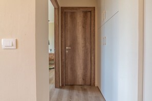 A hallway with a wooden door, a light switch, and a cabinet. - APPARTAMENTI IL SENTIERO DEL GRANITO - GRANITO BILO 1 DX (Campo nell'Elba)