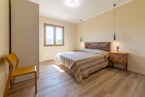 Una camera da letto con un letto, una sedia, un comodino e una finestra.