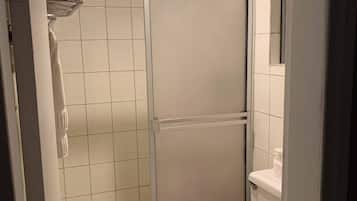 Baño con cabina de ducha, inodoro y perchero para toallas.