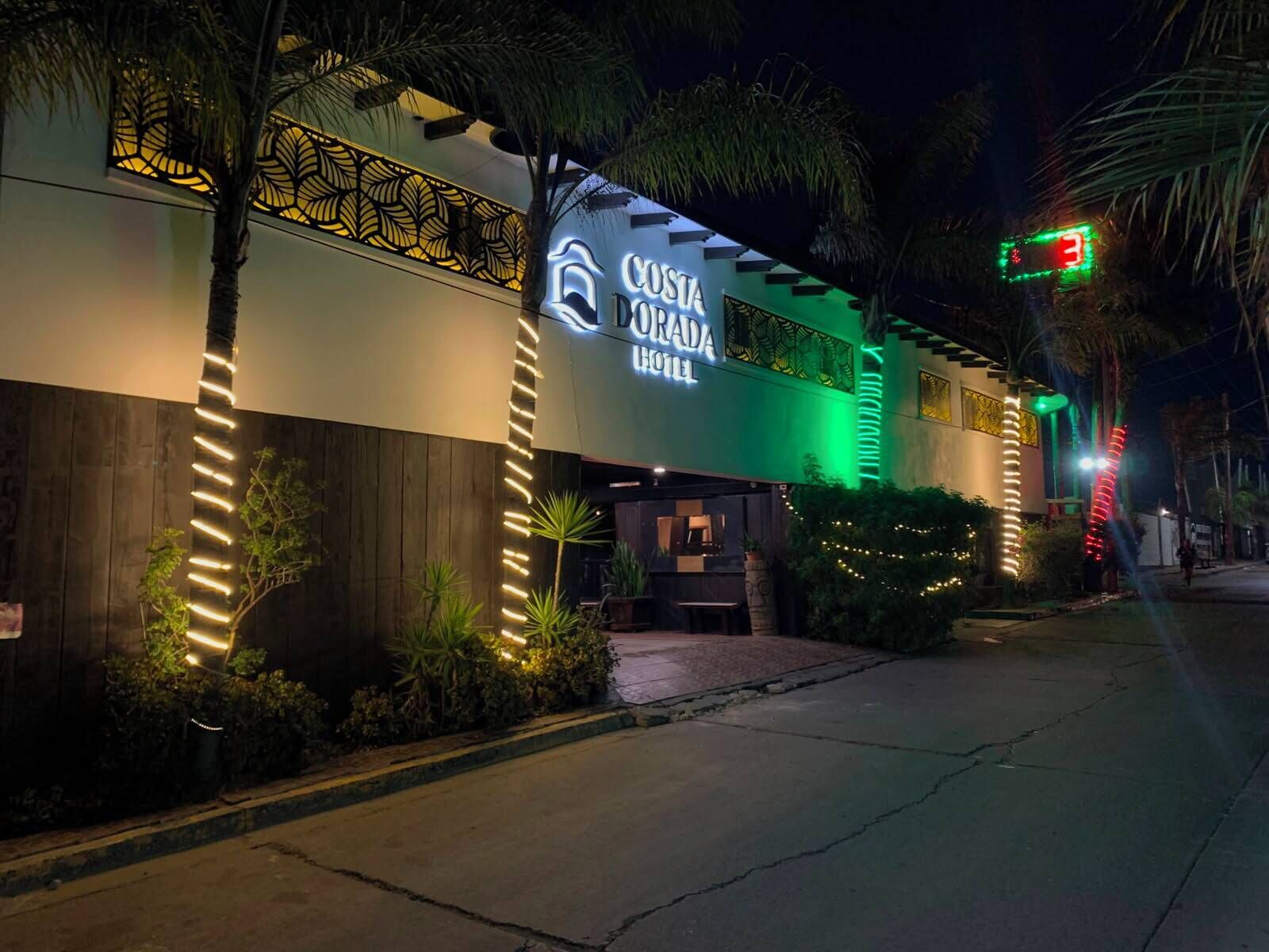 Hotel Costa Dorada, con fachada moderna, señalización iluminada y una entrada bien iluminada.