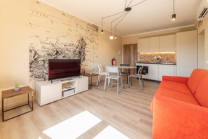 A modern living room with a flat-screen TV, a red sofa, and a dining area with a white table and chairs. - APPARTAMENTI IL SENTIERO DEL GRANITO - GRANITO BILO 2 SX (Campo nell'Elba)