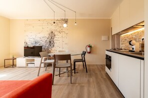 A modern kitchen with a map on the wall, a dining area with chairs, and a red sofa. - APPARTAMENTI IL SENTIERO DEL GRANITO - GRANITO BILO 2 SX (Campo nell'Elba)