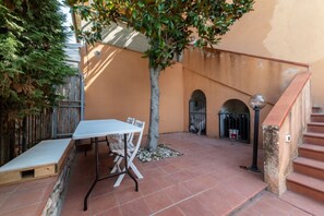 Eine Terrasse im Freien mit Tisch und Stühlen, einem Baum und einer Treppe.