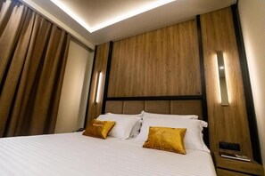 A hotel room with a bed, two pillows, a nightstand, and a wall-mounted light fixture. - Kraal Hotel Vlore (Vlorë)