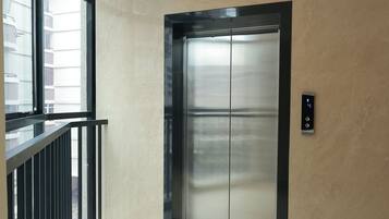 Un elevador moderno con detalles metálicos, situado en un edificio de fachada de vidrio.