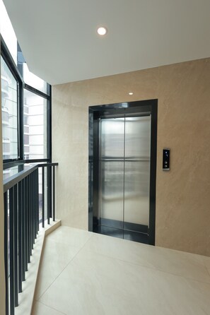Un elevador moderno con detalles metálicos, situado en un edificio de fachada de vidrio.