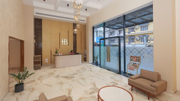 A hotel lobby with a reception desk, seating area, and a large window with a view of the outside.