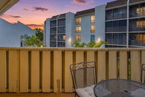 Ein Balkon mit Blick auf ein mehrstöckiges Gebäude, einem Metallstuhl und einem runden Tisch.