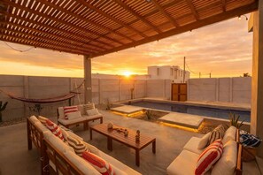 Terraza en la azotea con piscina, mobiliario exterior y una hamaca.