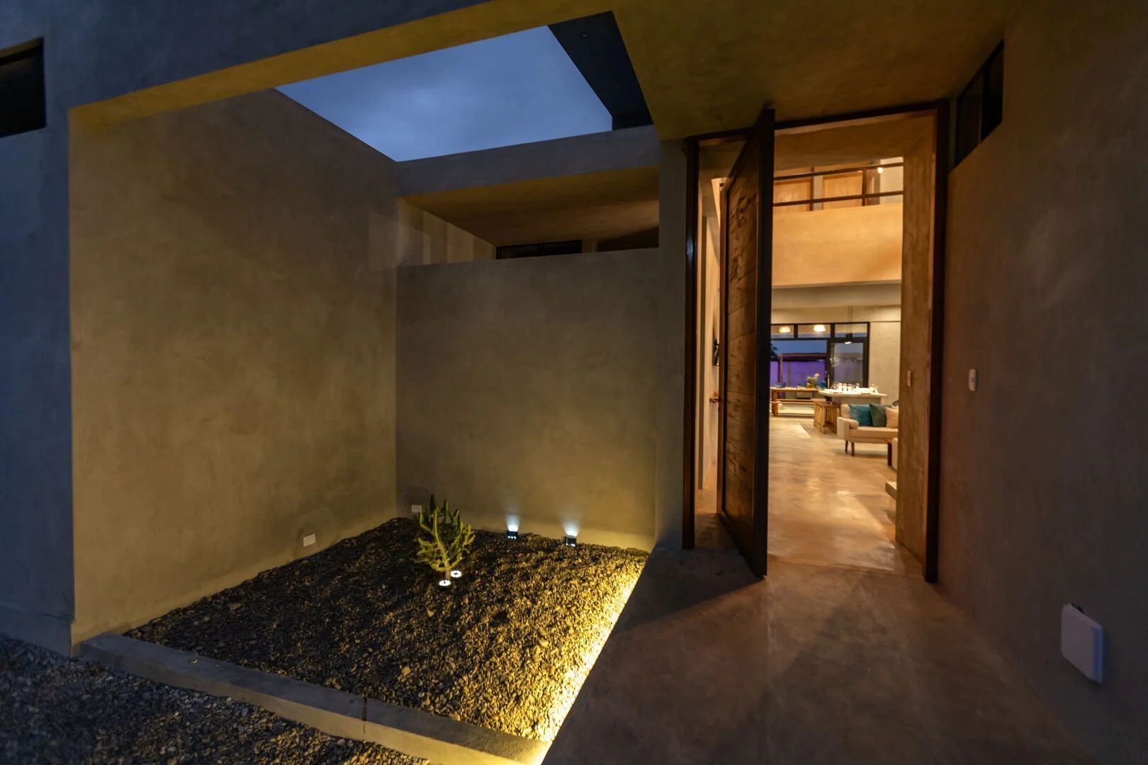 Un intérieur moderne agrémenté d’une verrière, d’un petit jardin intérieur et d’une vue sur un espace de vie aménagé avec des meubles.