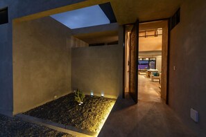 Un interior moderno con tragaluces, un pequeño jardín interior y vistas a una sala de estar con muebles.