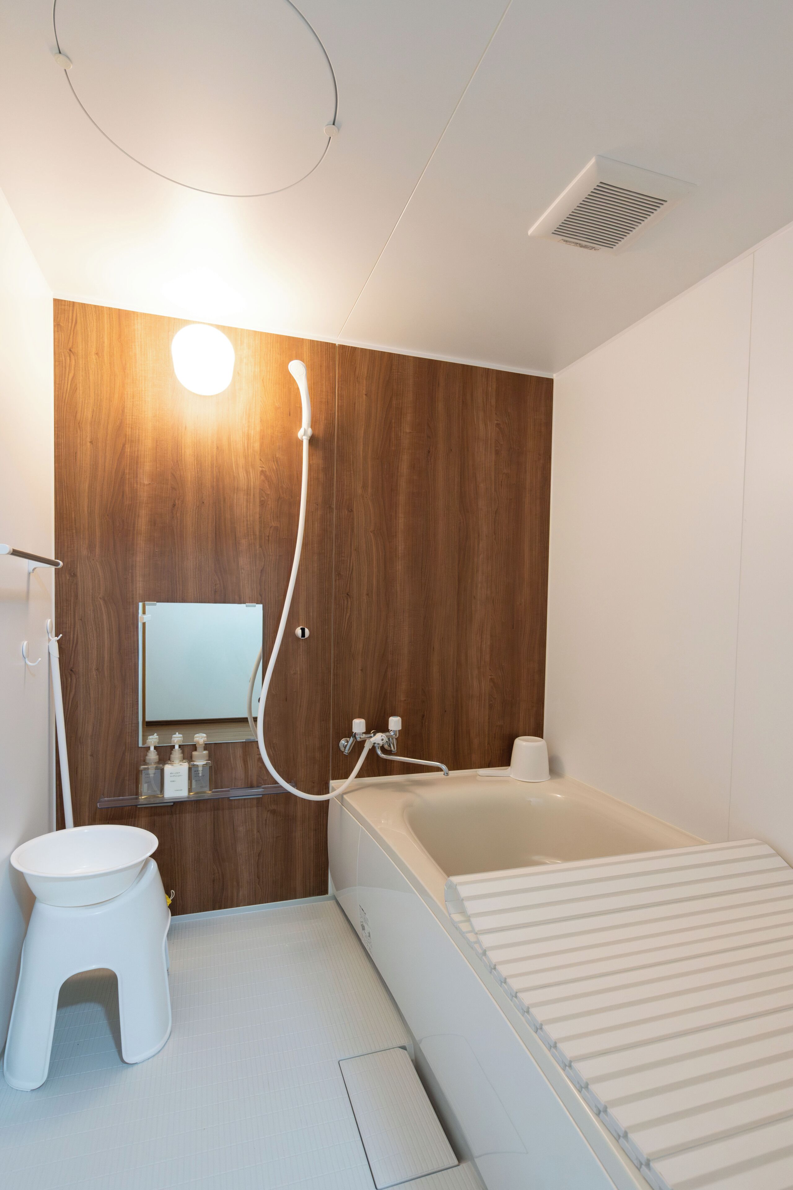 Un bagno moderno con una parete decorata in legno, un water bianco, un lavandino con specchio e una vasca da bagno.