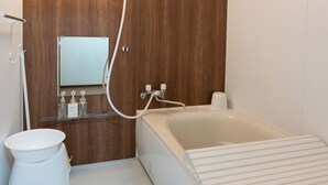 Ein modernes Badezimmer mit einer Wand aus Holz, einer weißen Toilette, einem Waschbecken mit Spiegel und einer Badewanne.