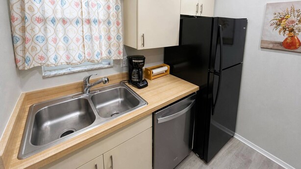 A kitchen with a double sink, a coffee maker, a black refrigerator, and a wooden countertop. - Renovated Condo Across from Siesta Key Beach | Heated Pool | Dogs Welcome (Siesta Key)