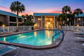 A hotel with a swimming pool, lounge chairs, and palm trees. - Renovated Condo Across from Siesta Key Beach | (Siesta Key)