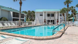 A swimming pool with lounge chairs and a building with a clock. - Renovated Condo Across from Siesta Key Beach | Heated Pool | Dogs Welcome (Siesta Key)